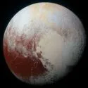 Et billede af Pluto i høj opløsning viser planetens overflade med rødlige og hvidlige områder, herunder et stort hjerteformet område, der står i kontrast til rummets mørke.