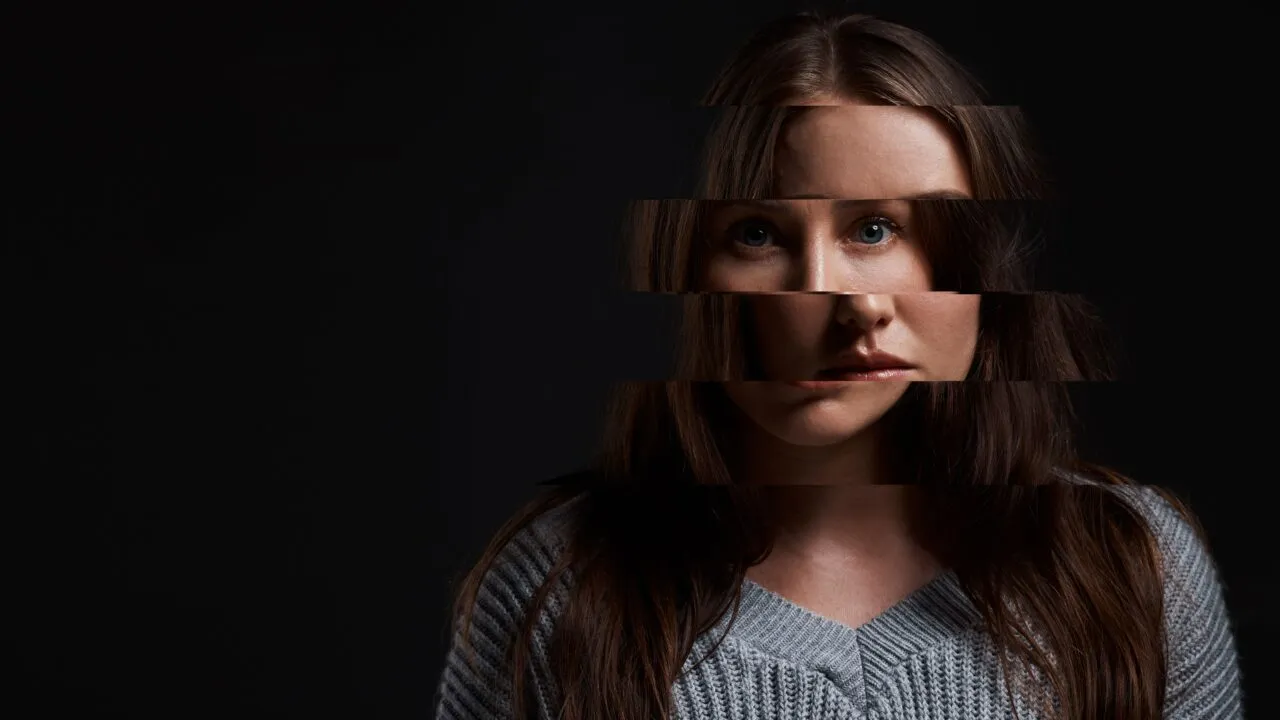 Der ses en kvinde med langt brunt hår på en mørk baggrund, hvor hendes ansigt er blevet skåret digitalt op i vandrette strimler, der ikke ligger på linje med hinanden, hvilket skaber en fragmenteret, surrealistisk effekt.