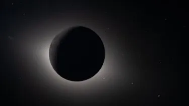 En mørk, skyggefuld planet eller måne er omgivet af en lysende glorie i rummet, som en solformørkelse set fra rummet, med mange svage stjerner spredt ud i baggrunden.