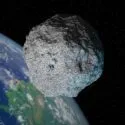 En stor grå asteroide svæver tæt på Jorden i det ydre rum, hvor en del af den blå og grønne planet kan ses på en sort baggrund.