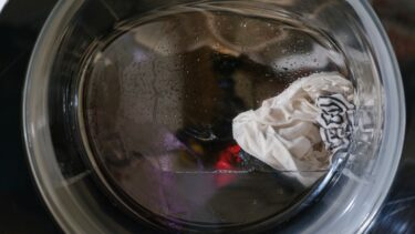 Billede af indersiden af en vaskemaskinetromle med et par fugtige hvide og mønstrede tøjstykker samlet i en bunke; der ses lidt fugt på tromlens overflade.