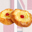 To wienerbrød med cremefyld og røde kirsebær ligger foran en falmet Union Jack-baggrund.