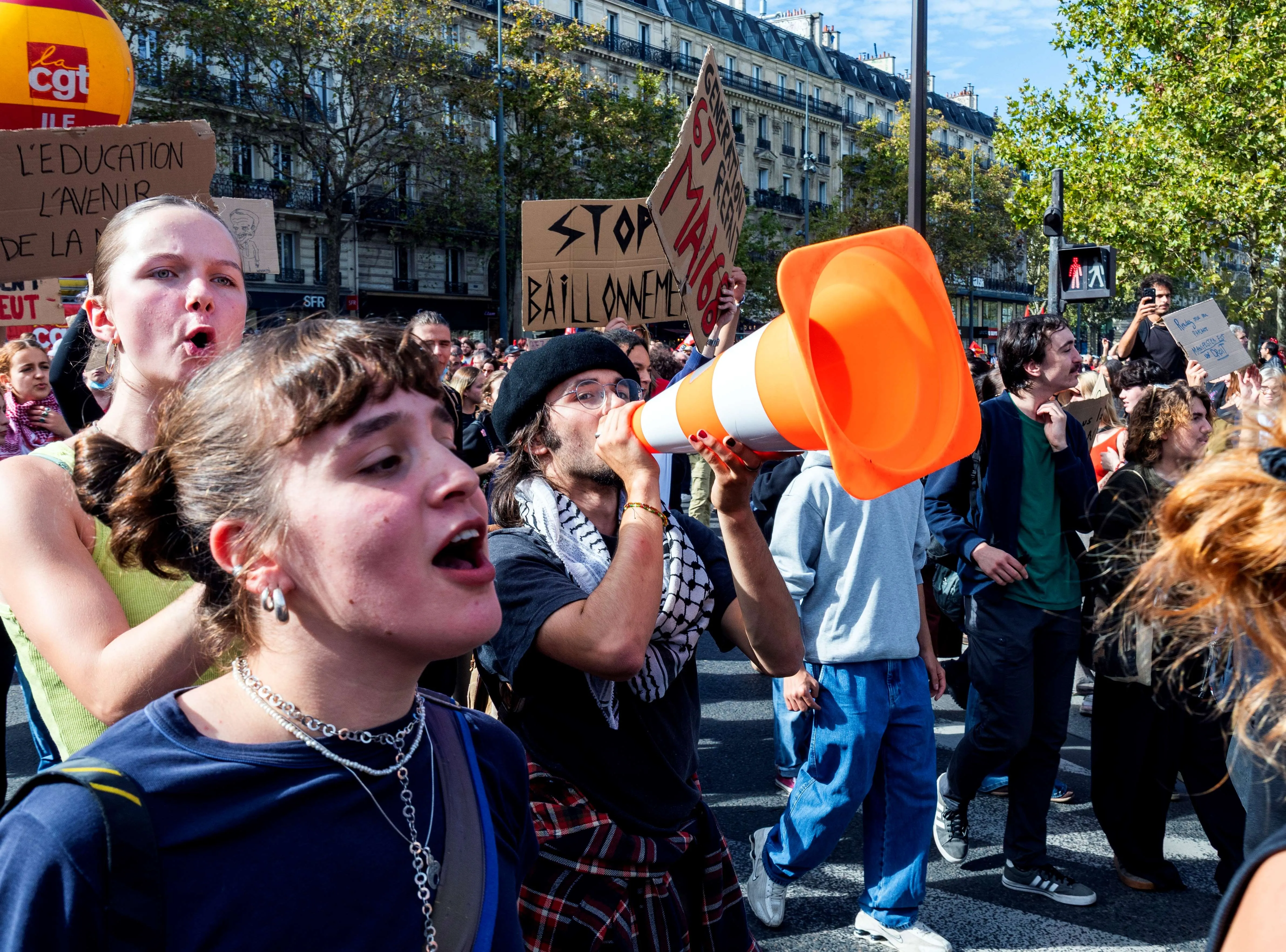 Demonstranter, der skanderer under en demonstration, hvor en person taler gennem en orange trafikkegle, der fungerer som megafon.