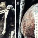 A: En arkæologisk grav med et menneskeskalle og lange knogler. B: Et nærbillede af en menneskeskalle med et lineært brud, målt med en lineal.